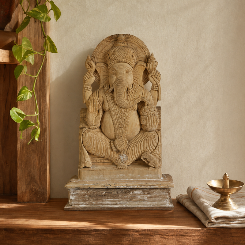 Hand-carved wooden Ganesh statue displayed on a warm home pooja shelf