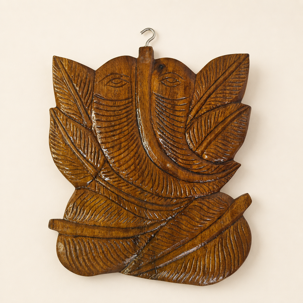 Hand-carved Bastar wooden Ganesha wall hanging on a warm ivory studio wall