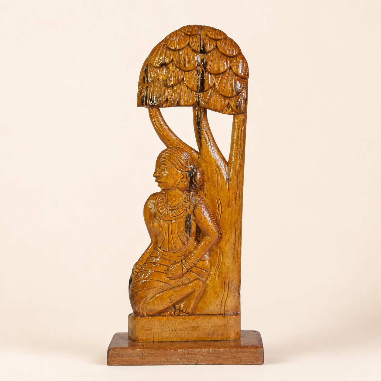 Bastar wood carving of a seated Madin tribal woman beneath a carved tree canopy on an ivory studio background