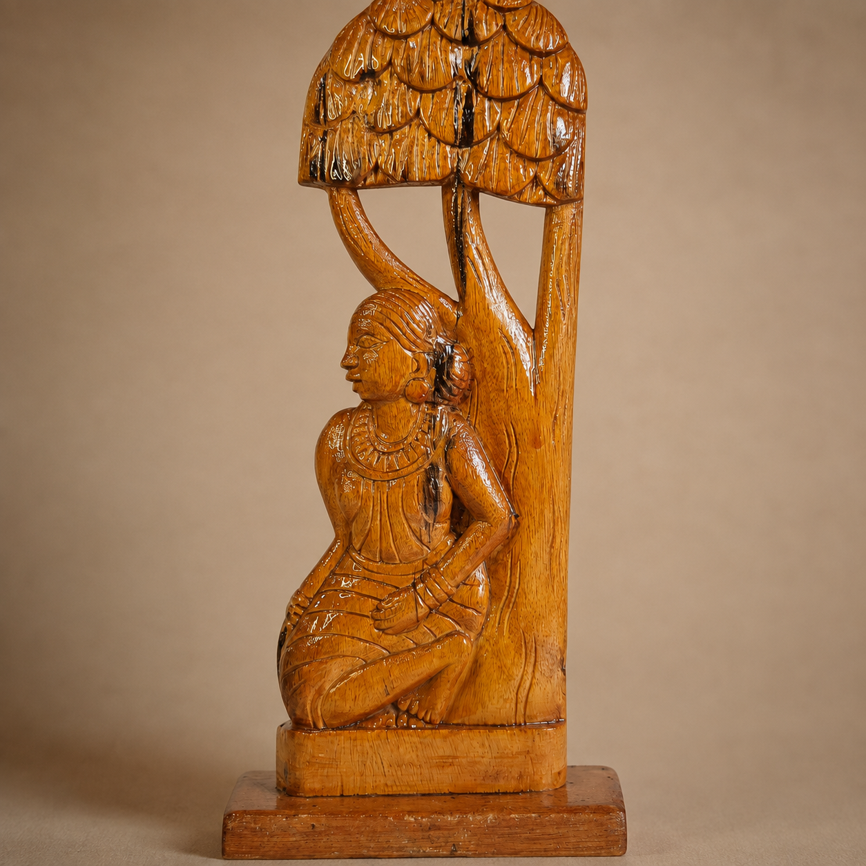 Close craftsmanship view of the carved woman, jewellery, wood grain and layered tree canopy