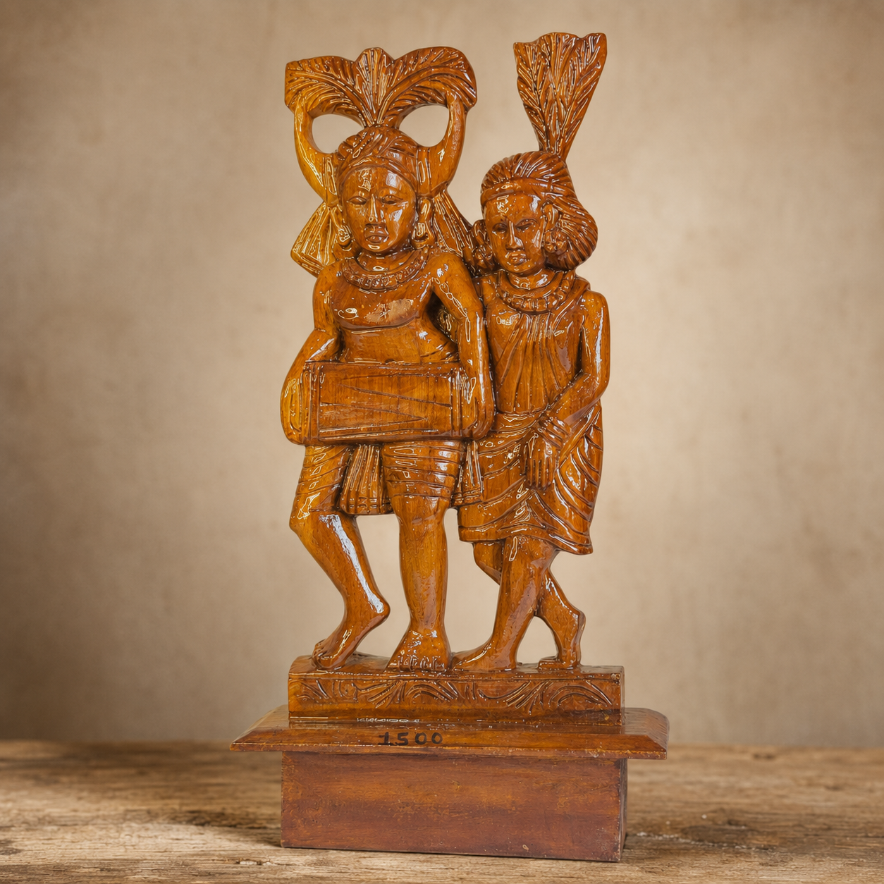 Carved headdresses, drum, garments and honey-toned wood grain of a Bastar musician sculpture