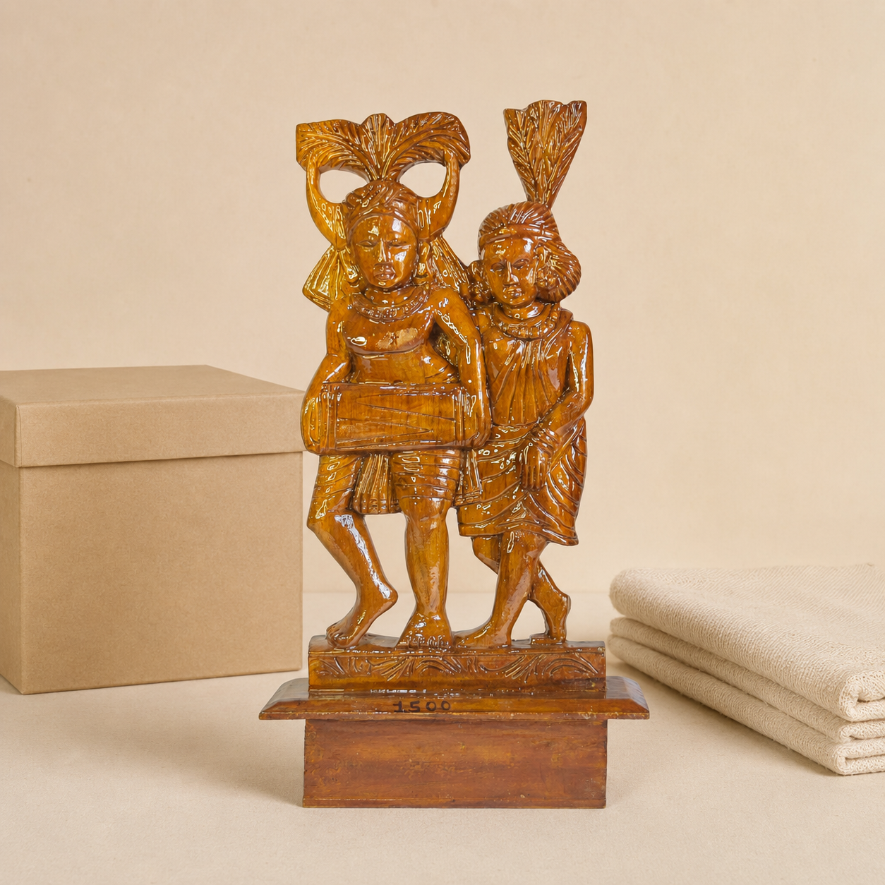 Bastar wood-carved musician couple sculpture presented beside a kraft gift box and handloom cloth