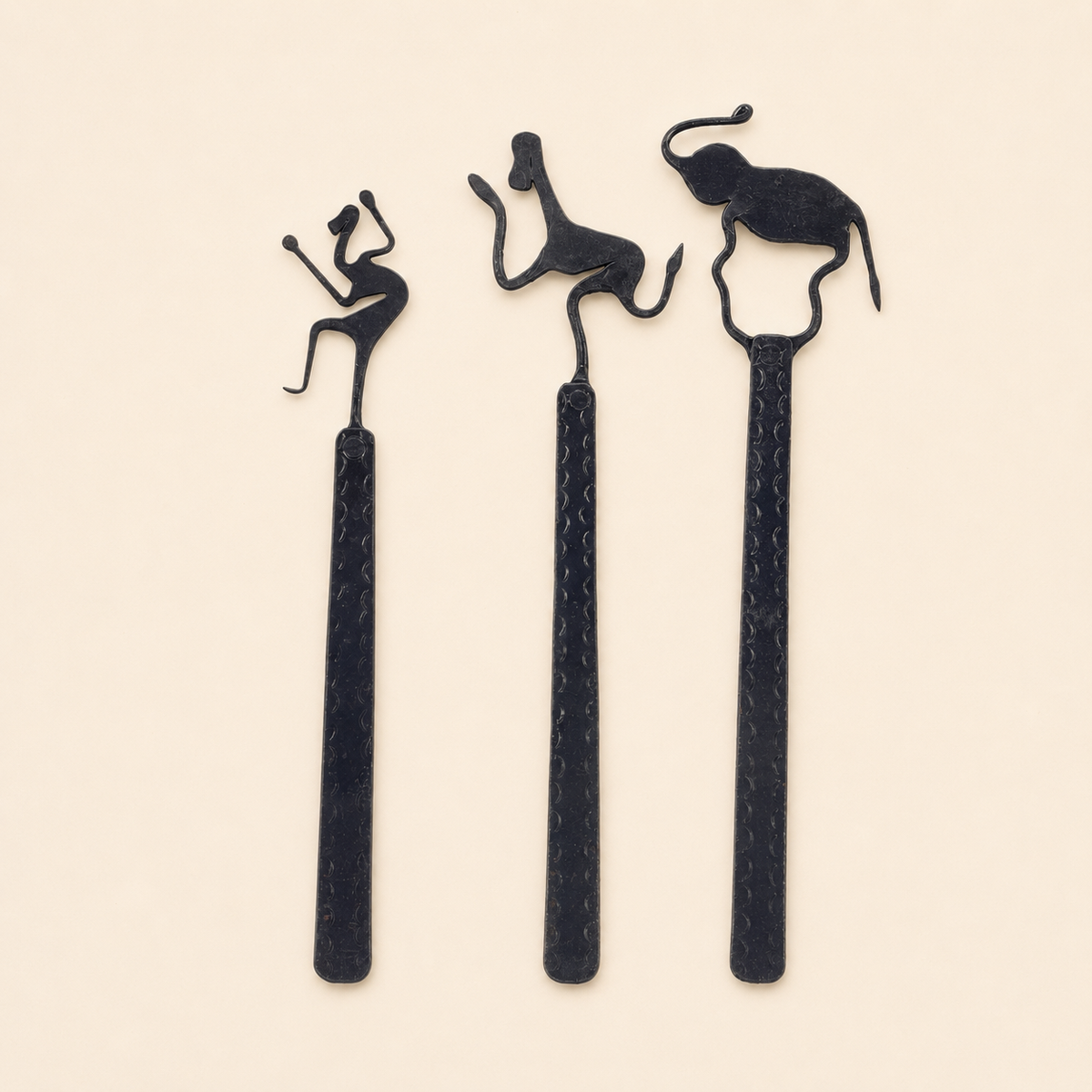 Three Bastar wrought iron bookmarks with musician, dancer, and elephant motifs on ivory