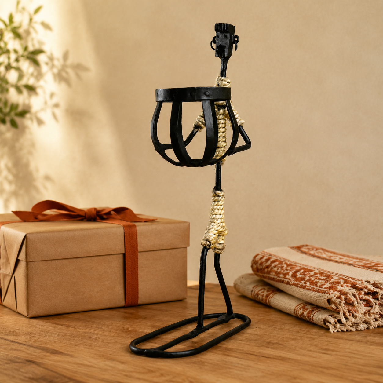 Bastar wrought iron tribal candle holder styled beside a kraft gift box and folded handloom cloth