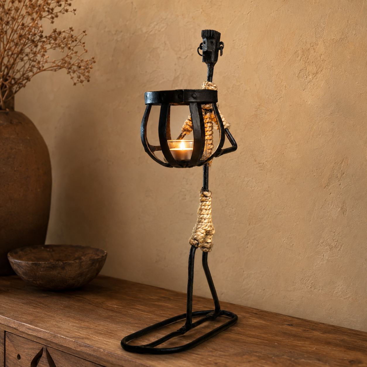Bastar wrought iron tribal candle holder glowing on a wooden console in a warm interior