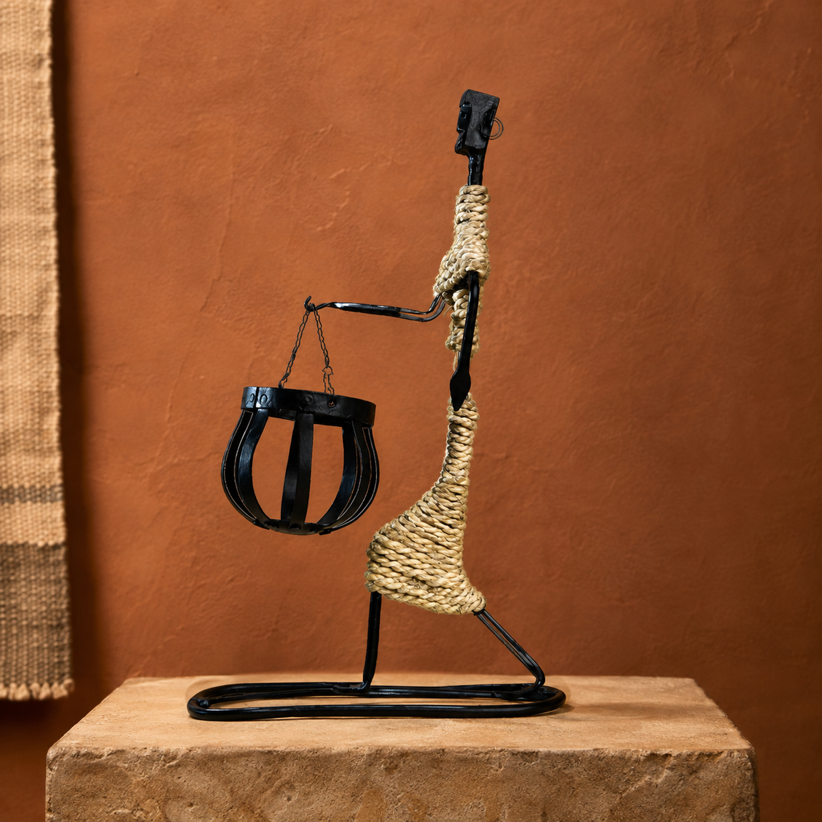 Bastar wrought iron profile figure candle holder presented on stone against a terracotta wall