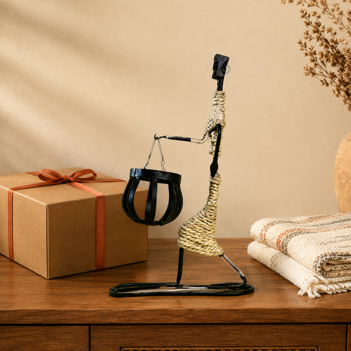 Bastar wrought iron profile figure candle holder beside a kraft gift box and folded handloom cloth