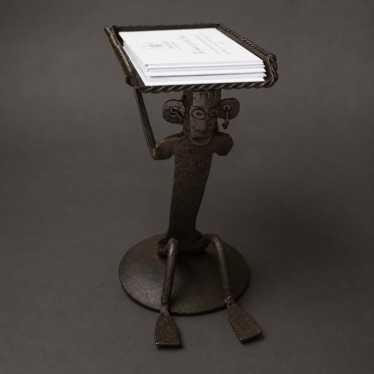 Close view of the forged tribal face and rope-edged tray on a Bastar iron card holder