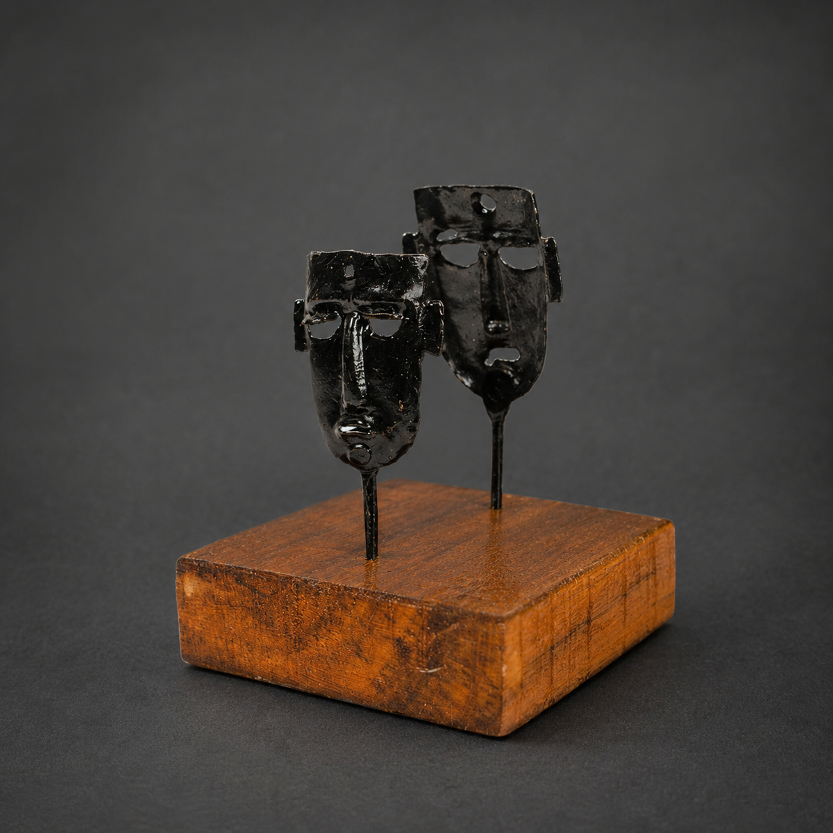 Detailed view of the forged masks, rods and wooden base of a Bastar card holder