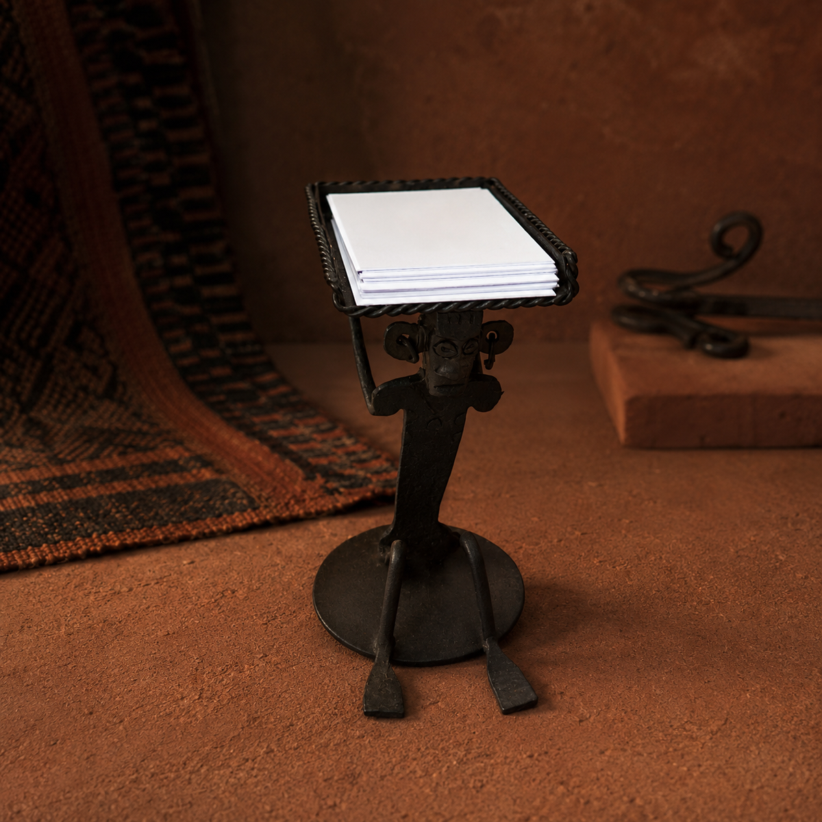 Bastar wrought iron card holder displayed with terracotta tones and a handwoven textile