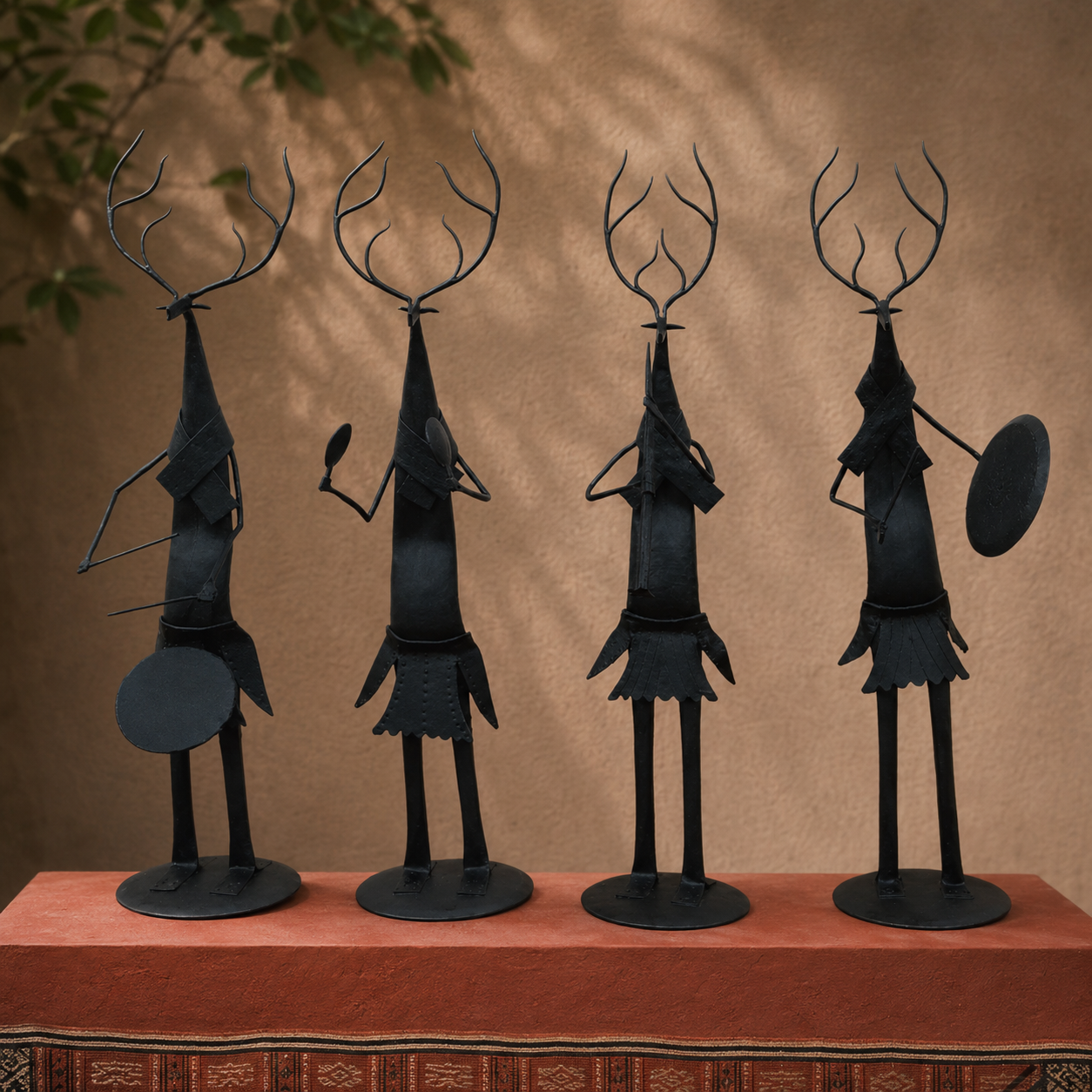 Four handcrafted Bastar iron deer musicians arranged on an ochre gallery plinth