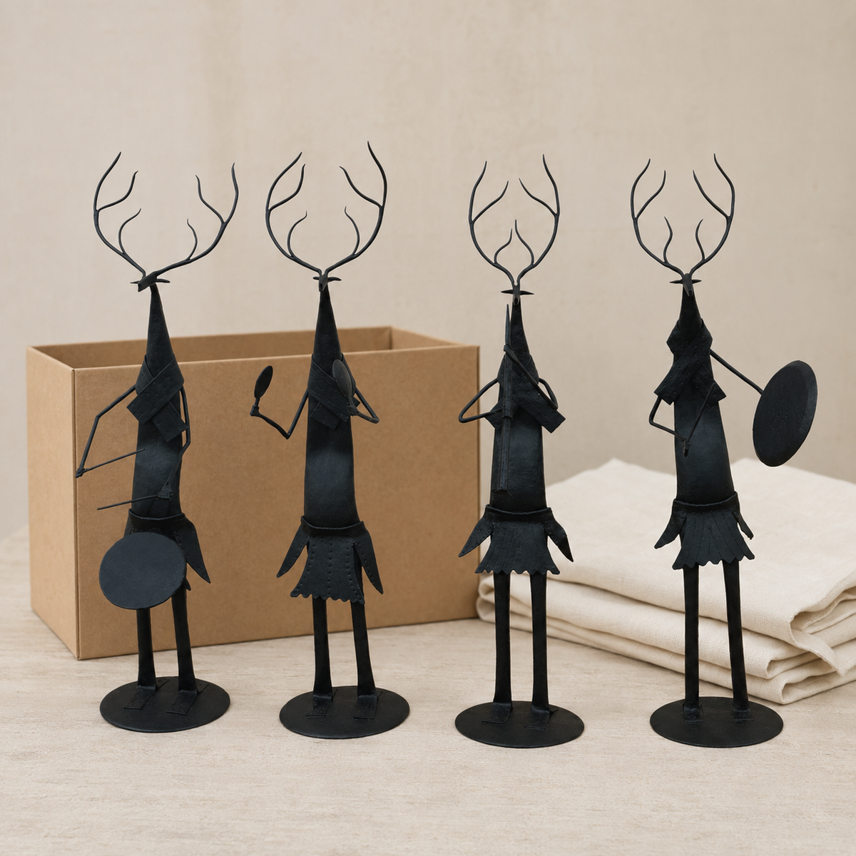 Four-piece Bastar wrought iron deer musician set presented beside a kraft gift box