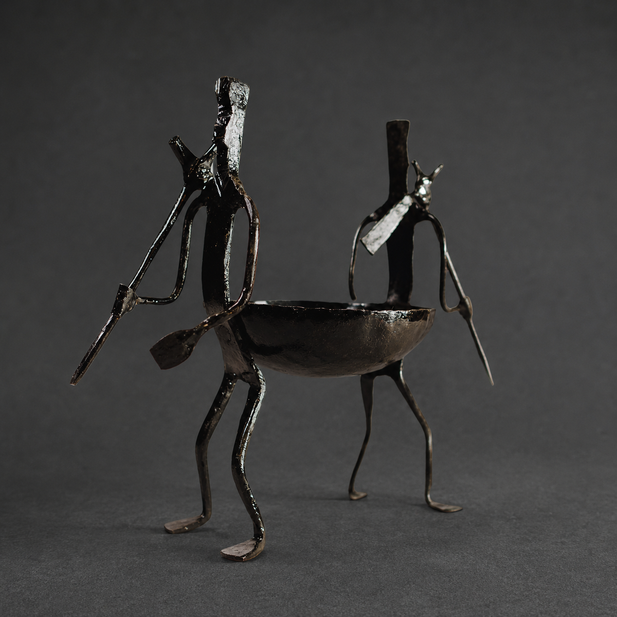 Detailed view of the forged bowl, two figures, utensils and patina of a Bastar dry fruit holder