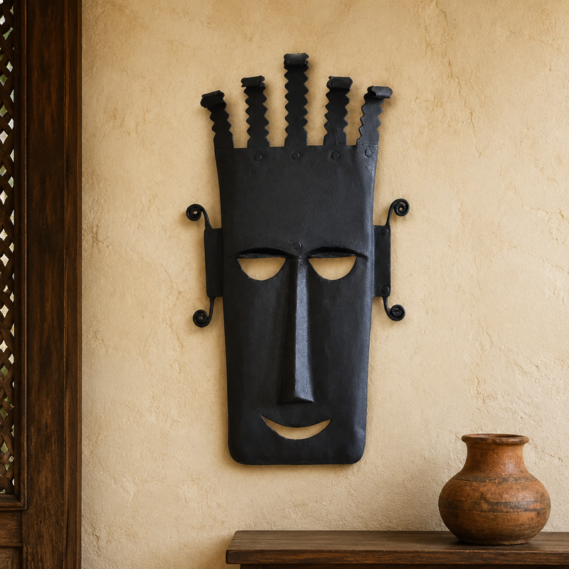 Bastar wrought iron face mask displayed on a warm plaster entryway wall