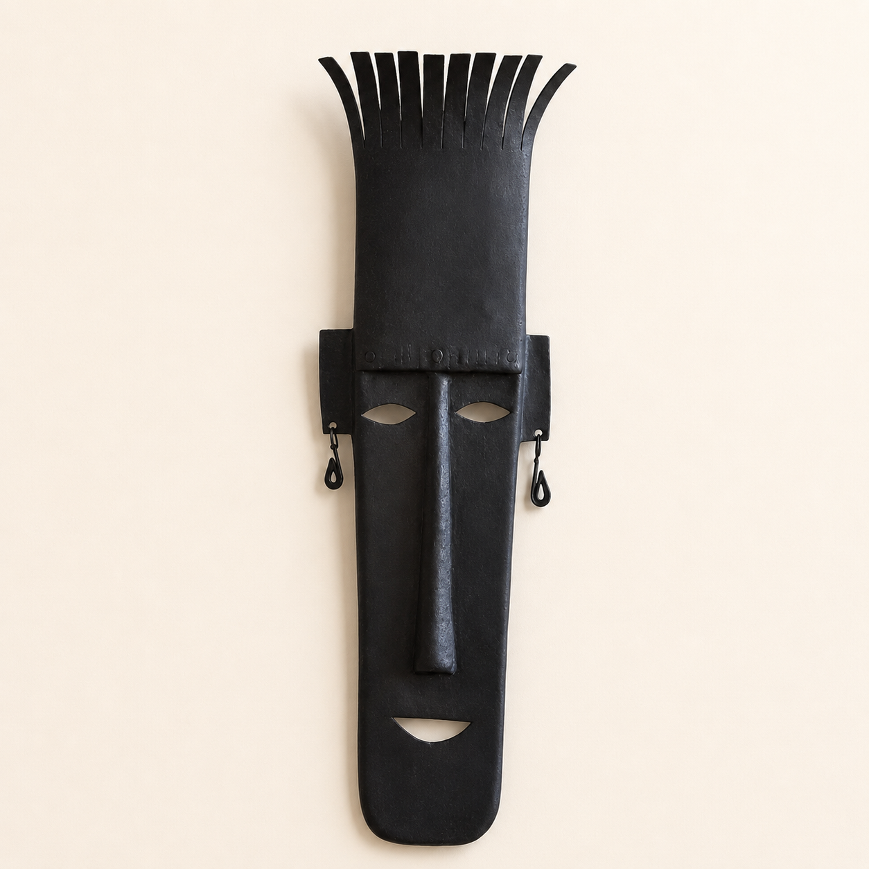 Bastar wrought iron face mask with tall crown and earrings on an ivory wall