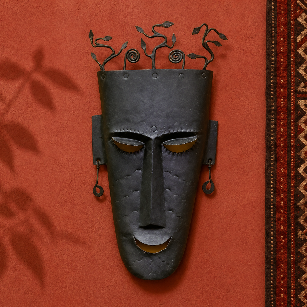 Hand-forged Bastar face mask presented on an ochre artisan gallery wall