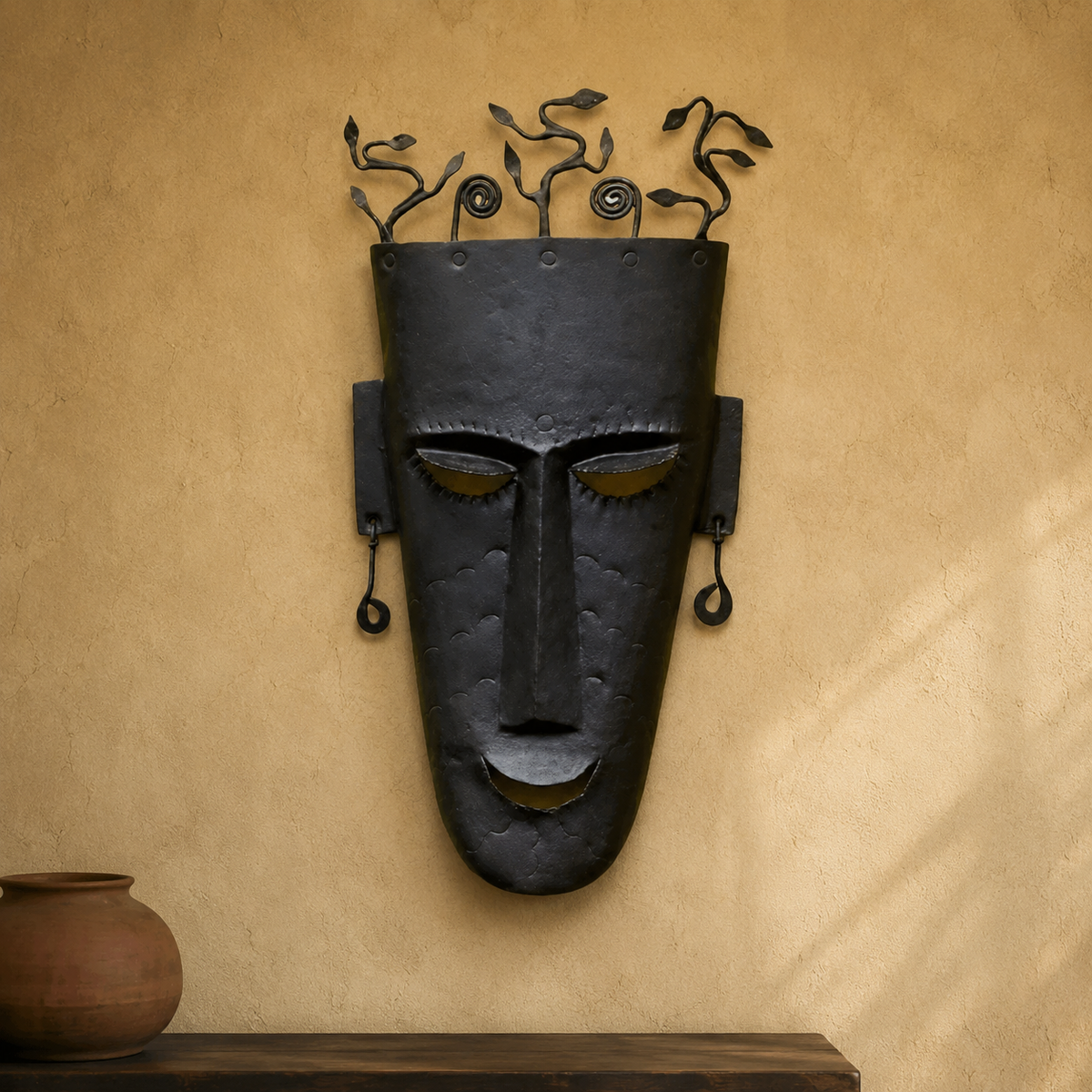 Bastar wrought iron face mask displayed on a warm plaster wall above a wooden console