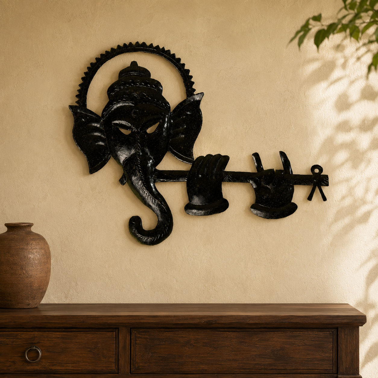 Hand-forged Ganesh wall art displayed above a wooden console in a warm interior