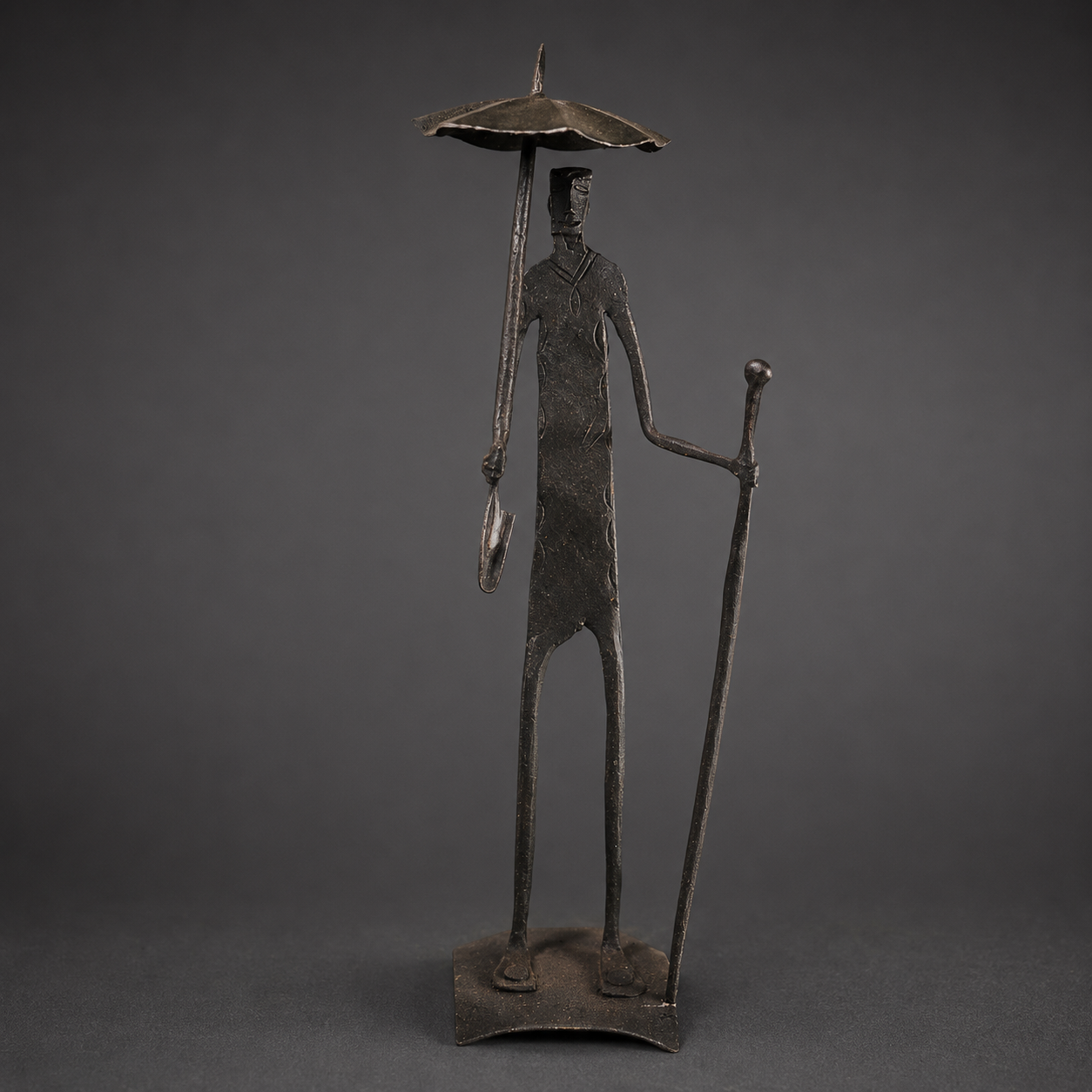 Detailed view of the umbrella, facial incisions, staff and patina of a Bastar iron figure