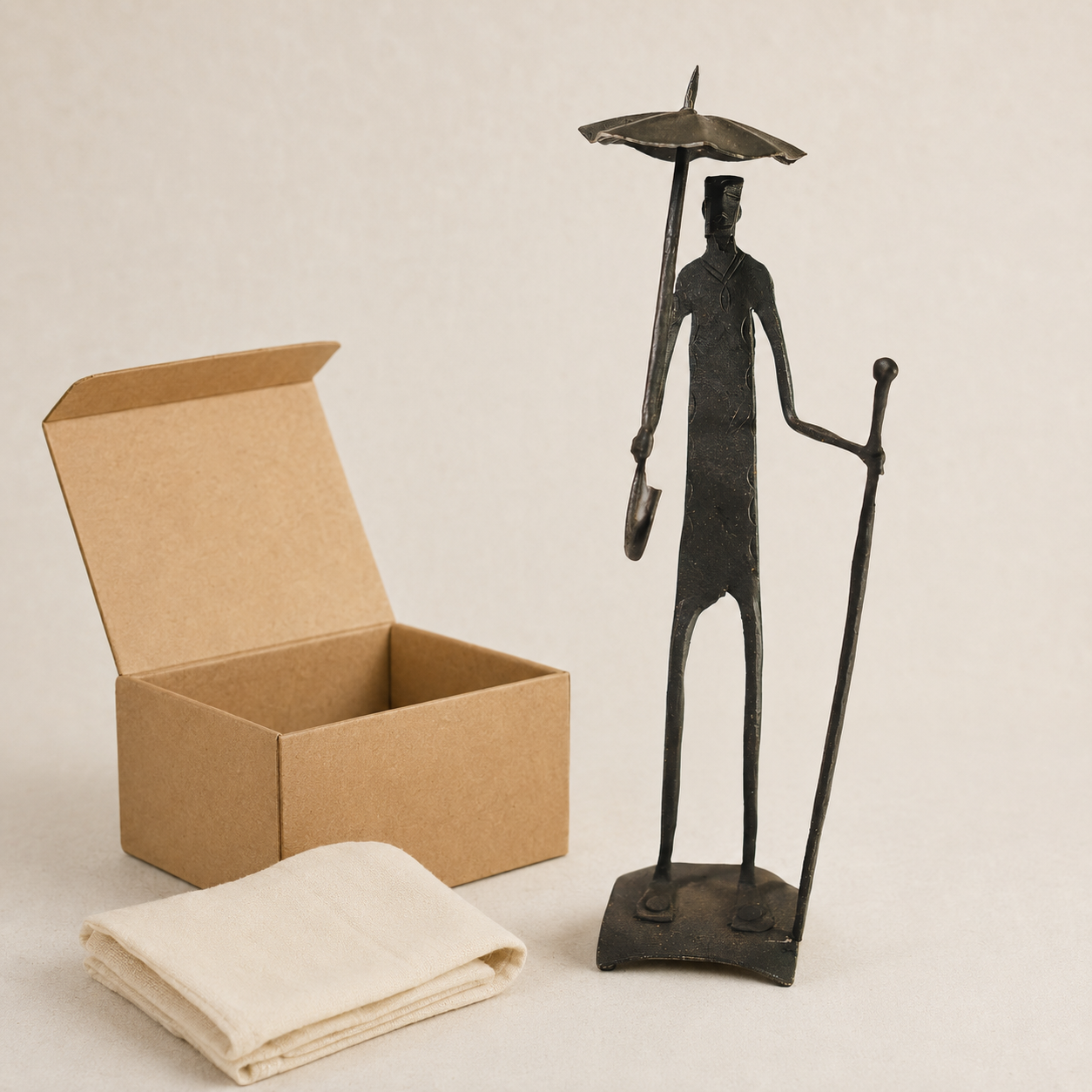 Bastar wrought iron human figure sculpture presented beside a kraft gift box