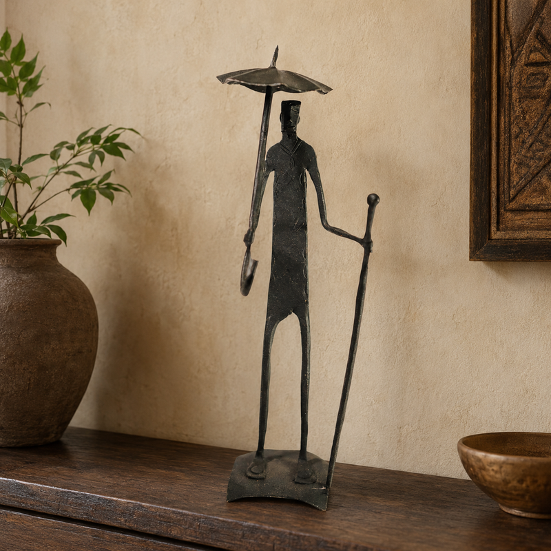 Tall Bastar iron human figure displayed on a wooden console in a warm interior