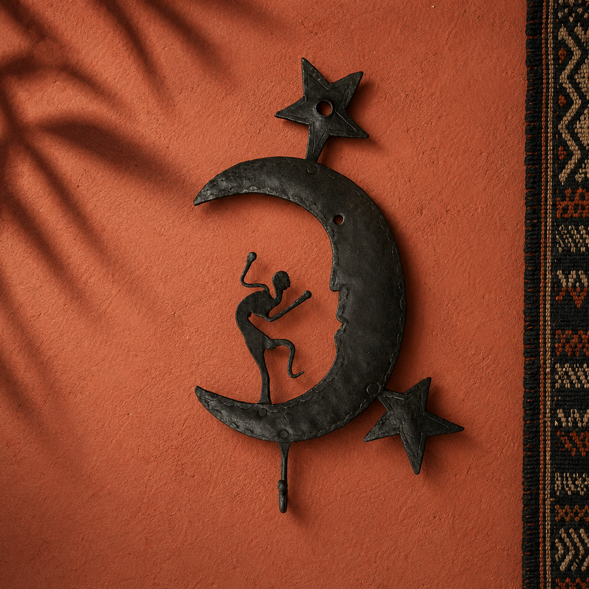 Hand-forged crescent and dancer key hanger displayed on an ochre artisan wall