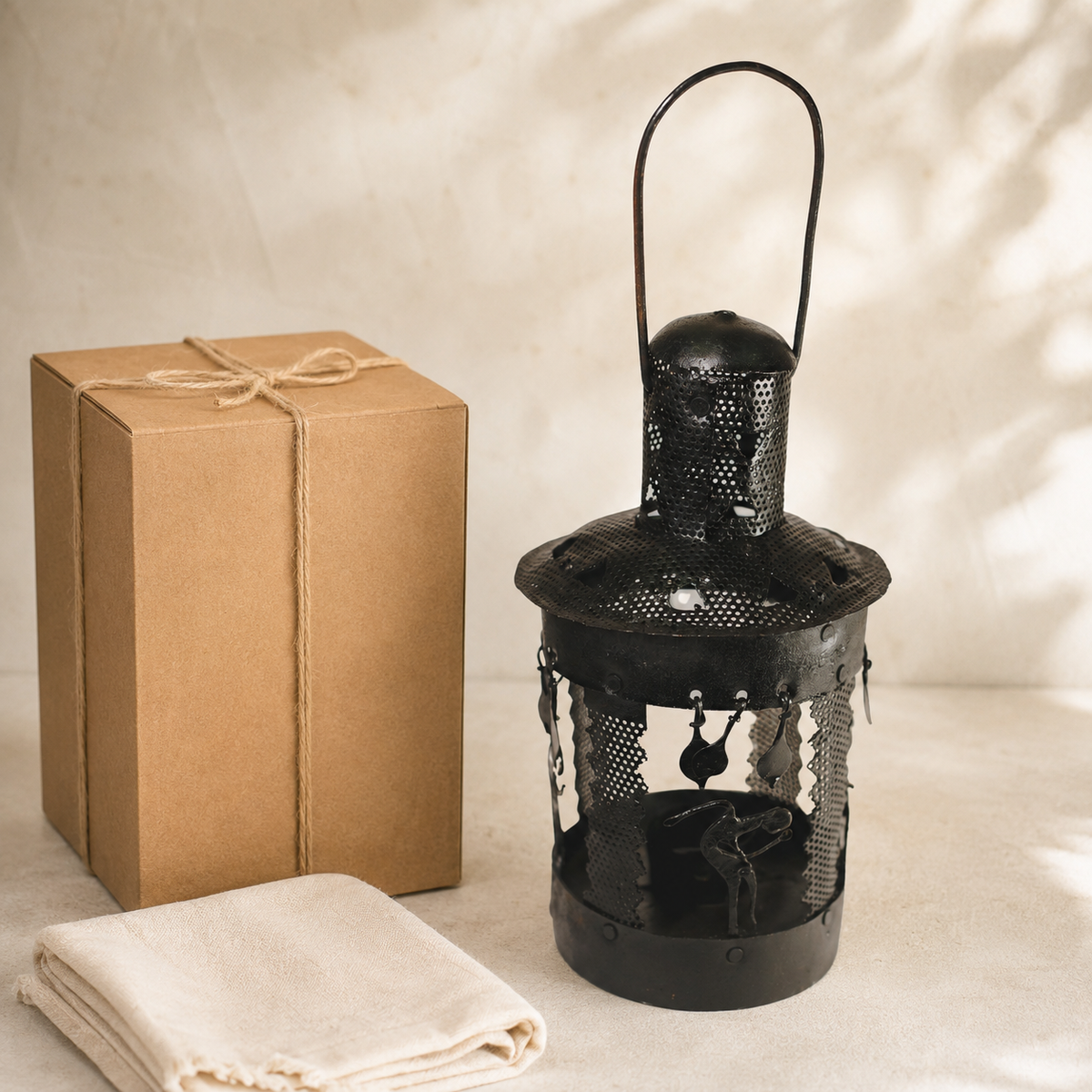 Bastar wrought iron lantern displayed beside a kraft gift box and cotton cloth