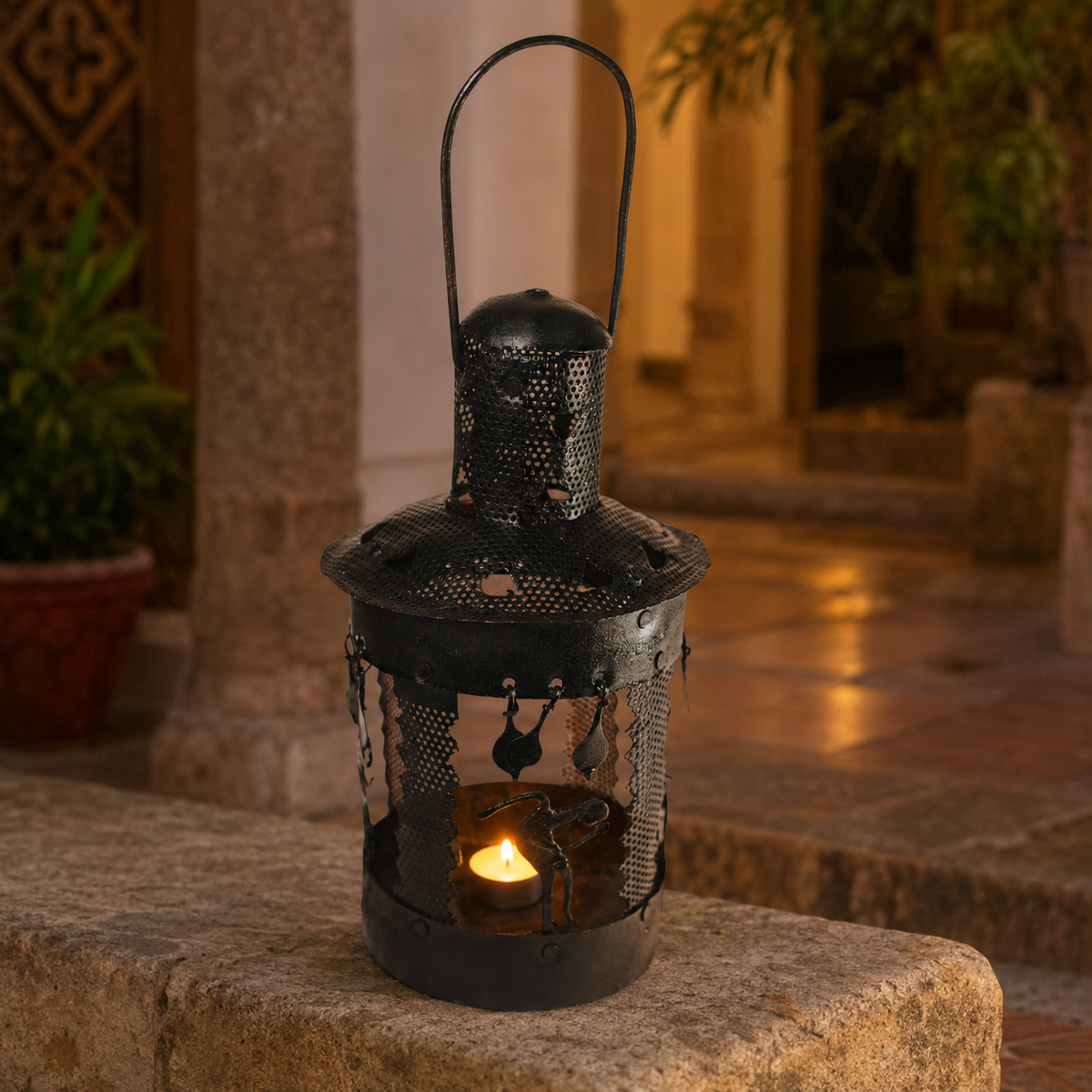 Bastar wrought iron lantern glowing on a stone ledge in an Indian courtyard