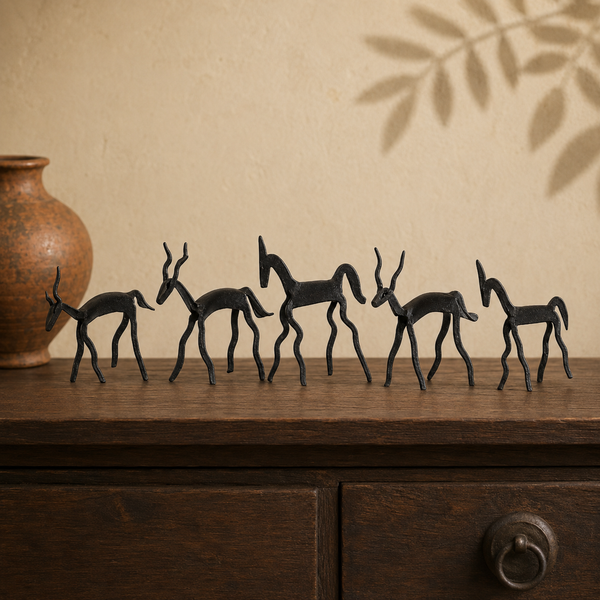 Five handcrafted iron animal figures displayed on a wooden console in a warm interior