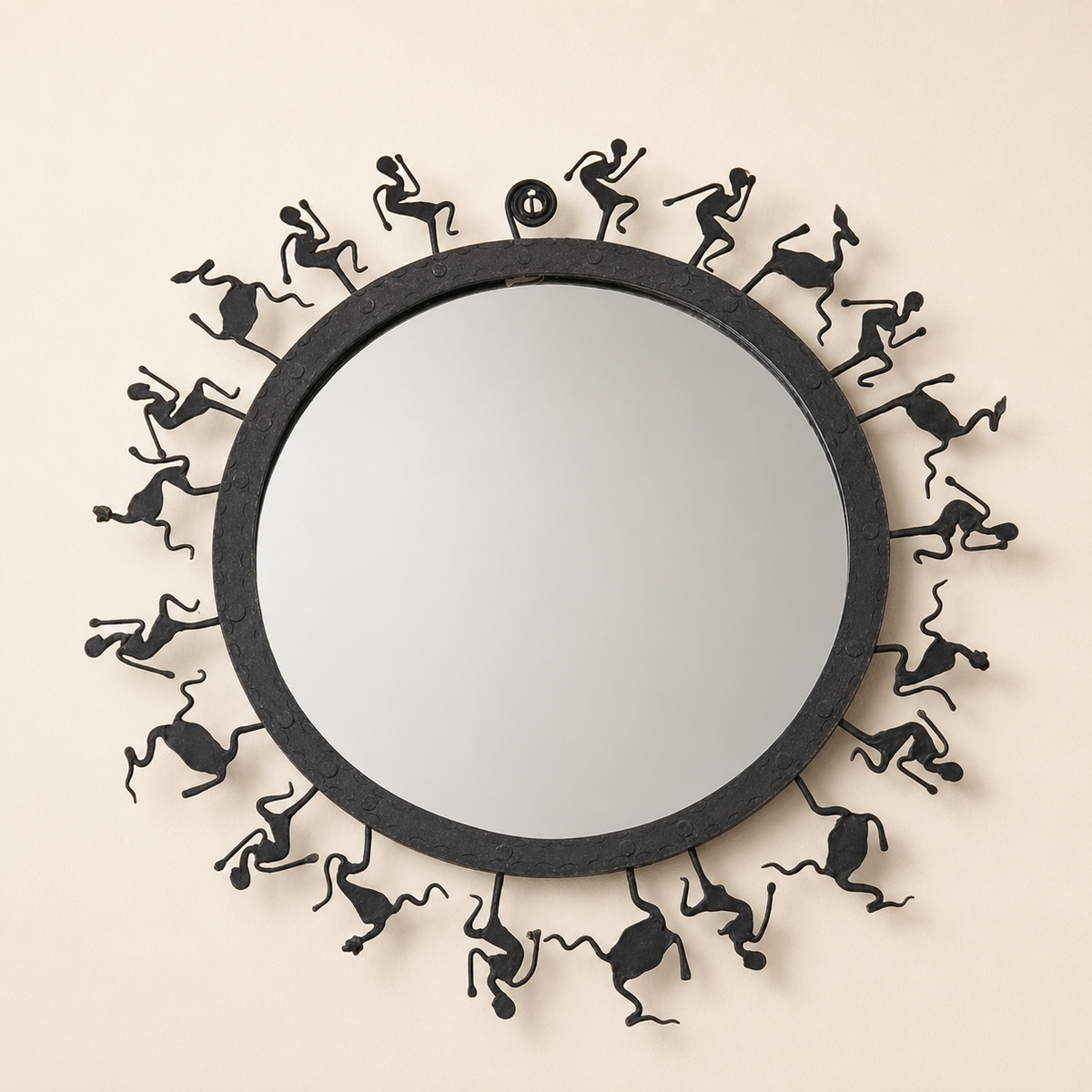 Circular Bastar wrought iron mirror frame with radial tribal figures on an ivory wall