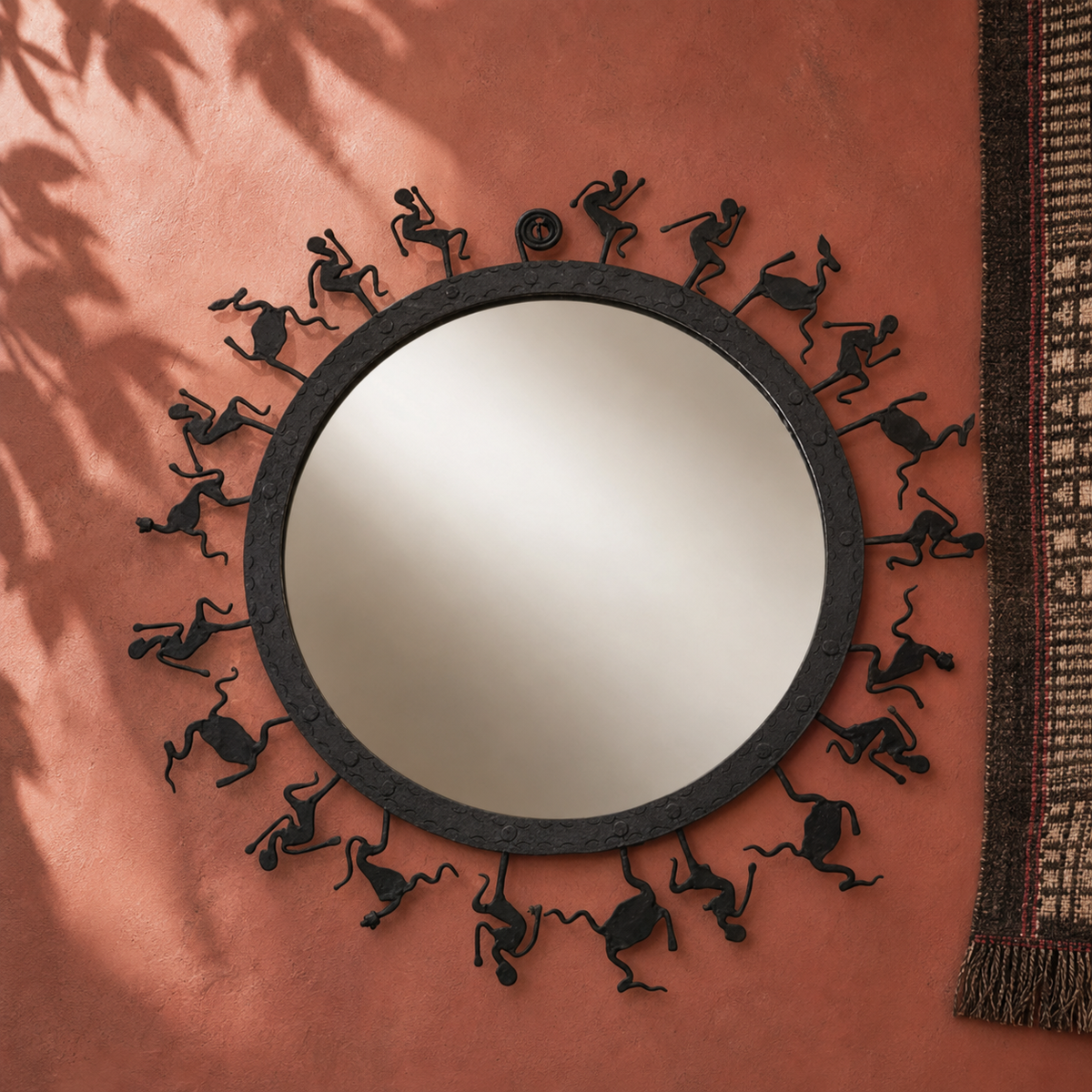 Hand-forged circular Bastar mirror frame displayed on an ochre gallery wall