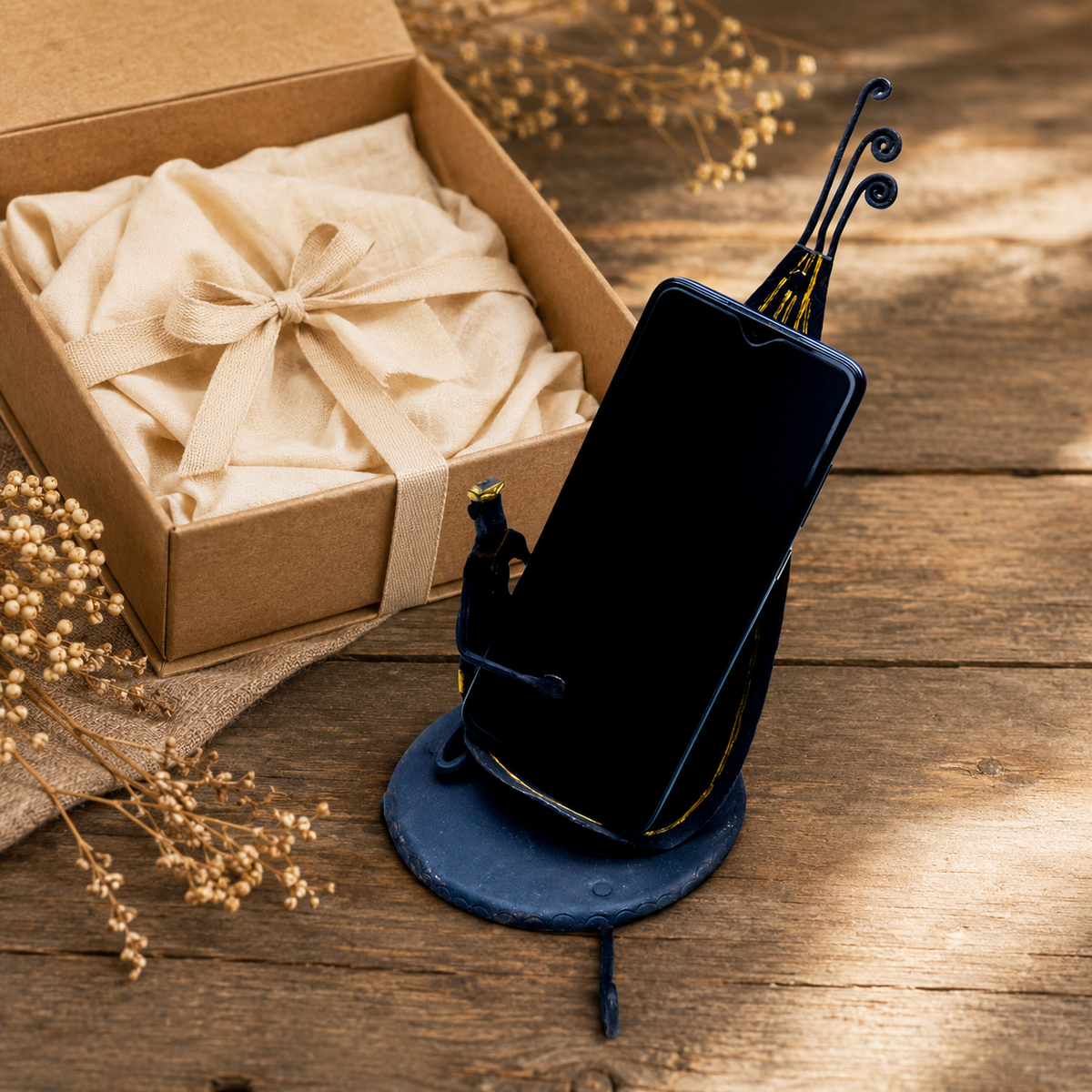 Bastar wrought iron mobile holder with a phone beside a wrapped gift box