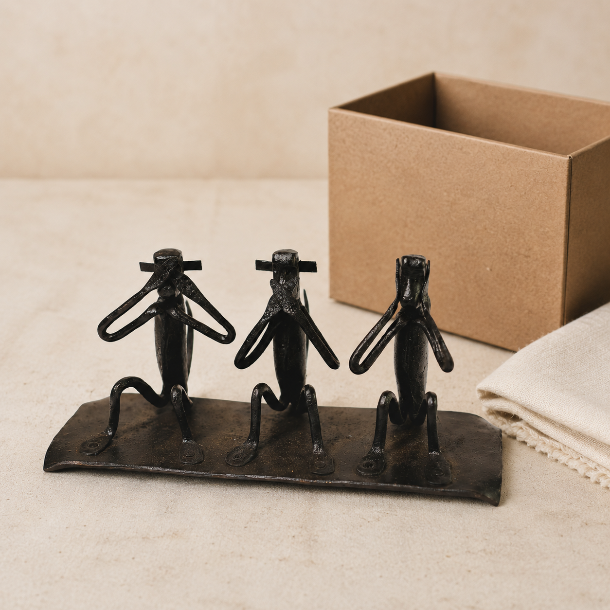 Bastar wrought iron three-monkey sculpture presented beside a kraft gift box