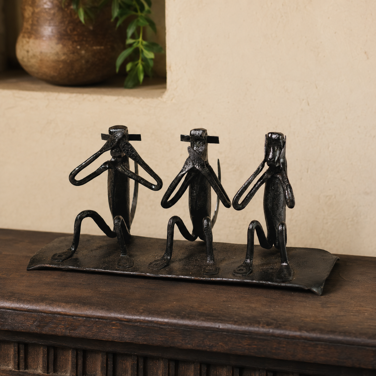 Bastar wrought iron three-monkey sculpture displayed on a wooden console