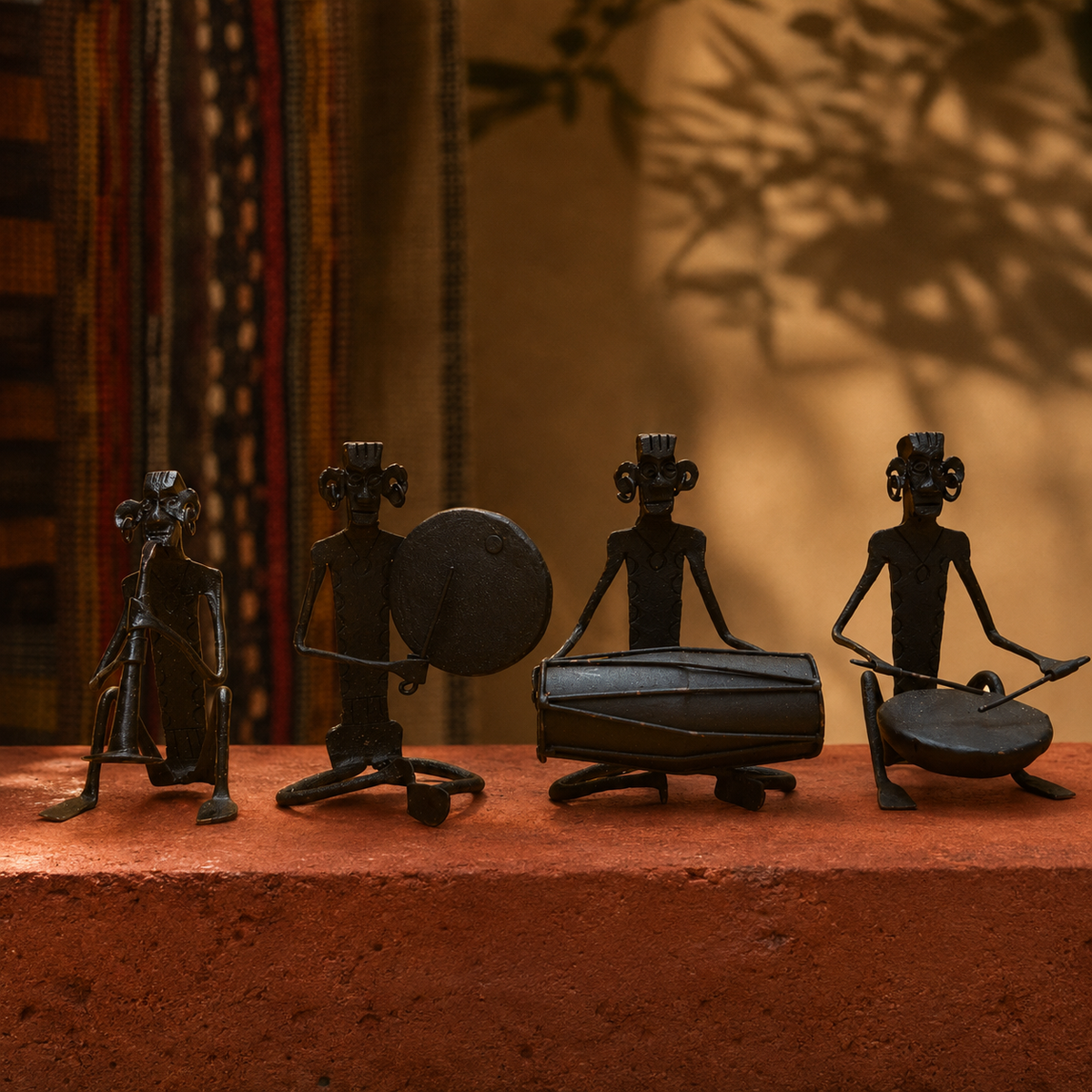 Four handcrafted Bastar iron musicians arranged on an ochre artisan gallery plinth