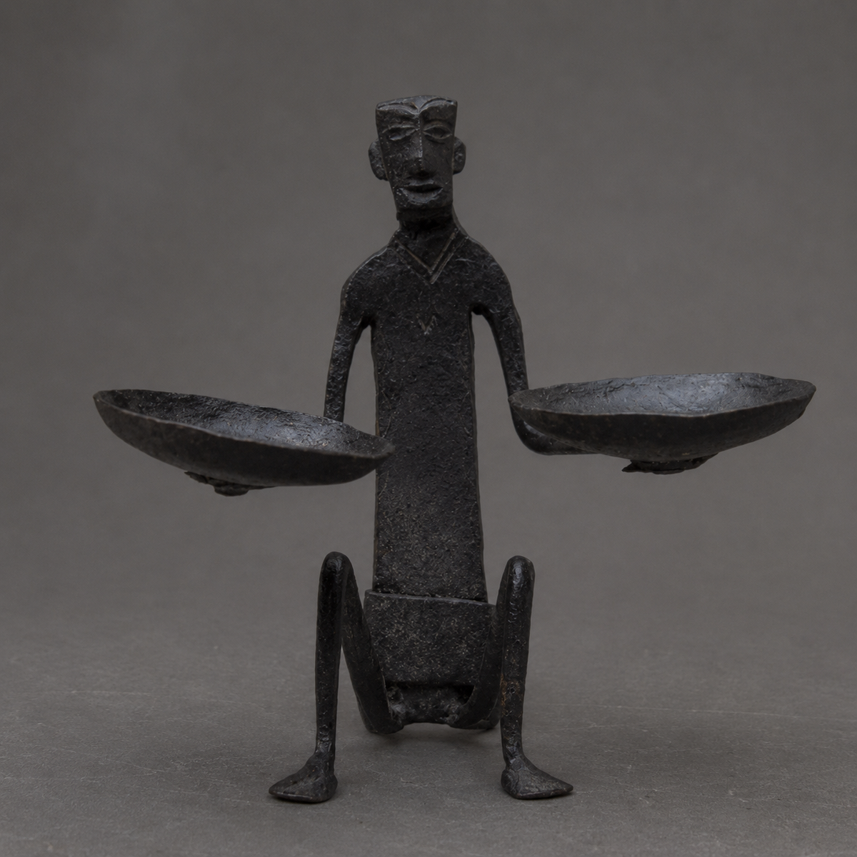 Detailed view of the forged bowls, figure and patina of a Bastar iron candle holder