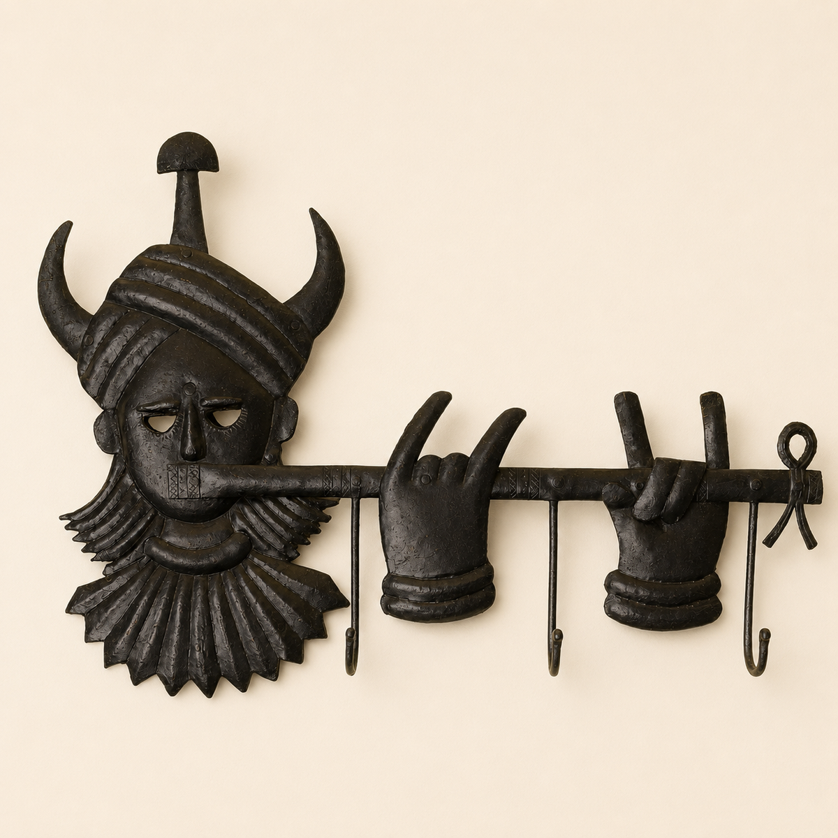 Bastar wrought iron tribal key hanger with horned face and three hooks on an ivory wall