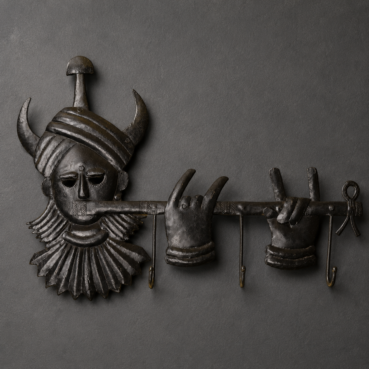 Detailed view of the horned face, figures, rivets and hooks of a Bastar iron key hanger