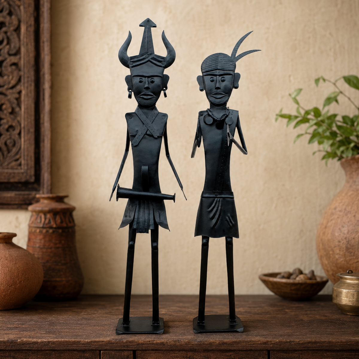 Two Bastar wrought iron tribal figures displayed on a wooden console in a warm interior