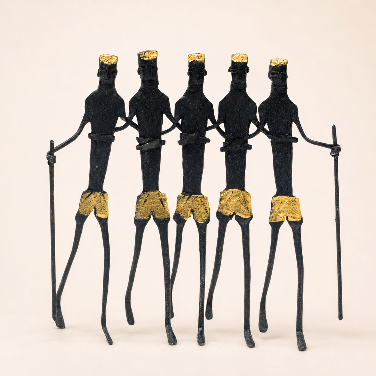 Five linked Bastar wrought iron tribal figures with gold accents on an ivory background