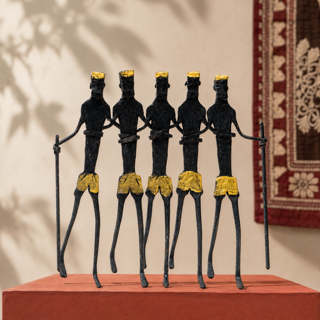 Linked Bastar iron tribal figures with two staffs on an ochre gallery plinth