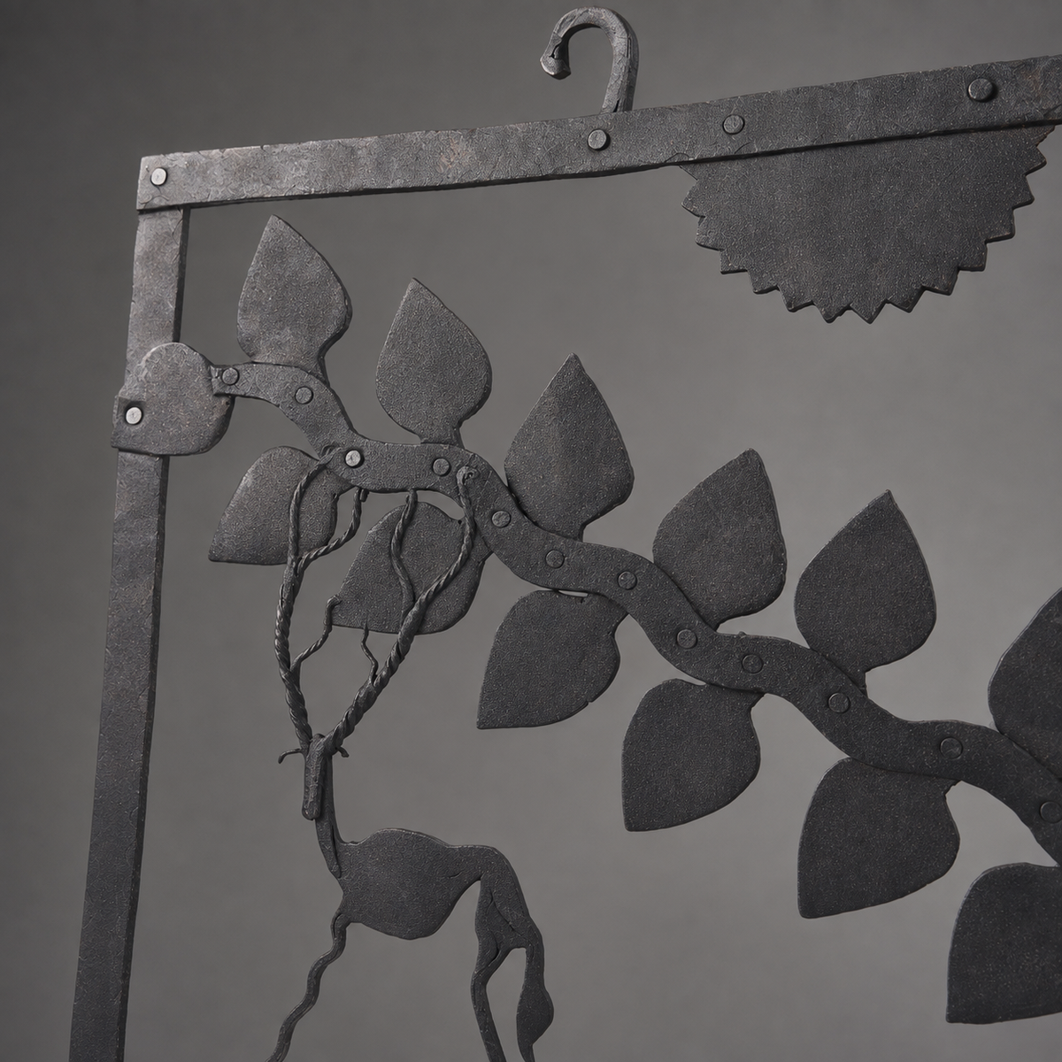 Close view of hand-forged iron rivets, leafy branch and deer detailing