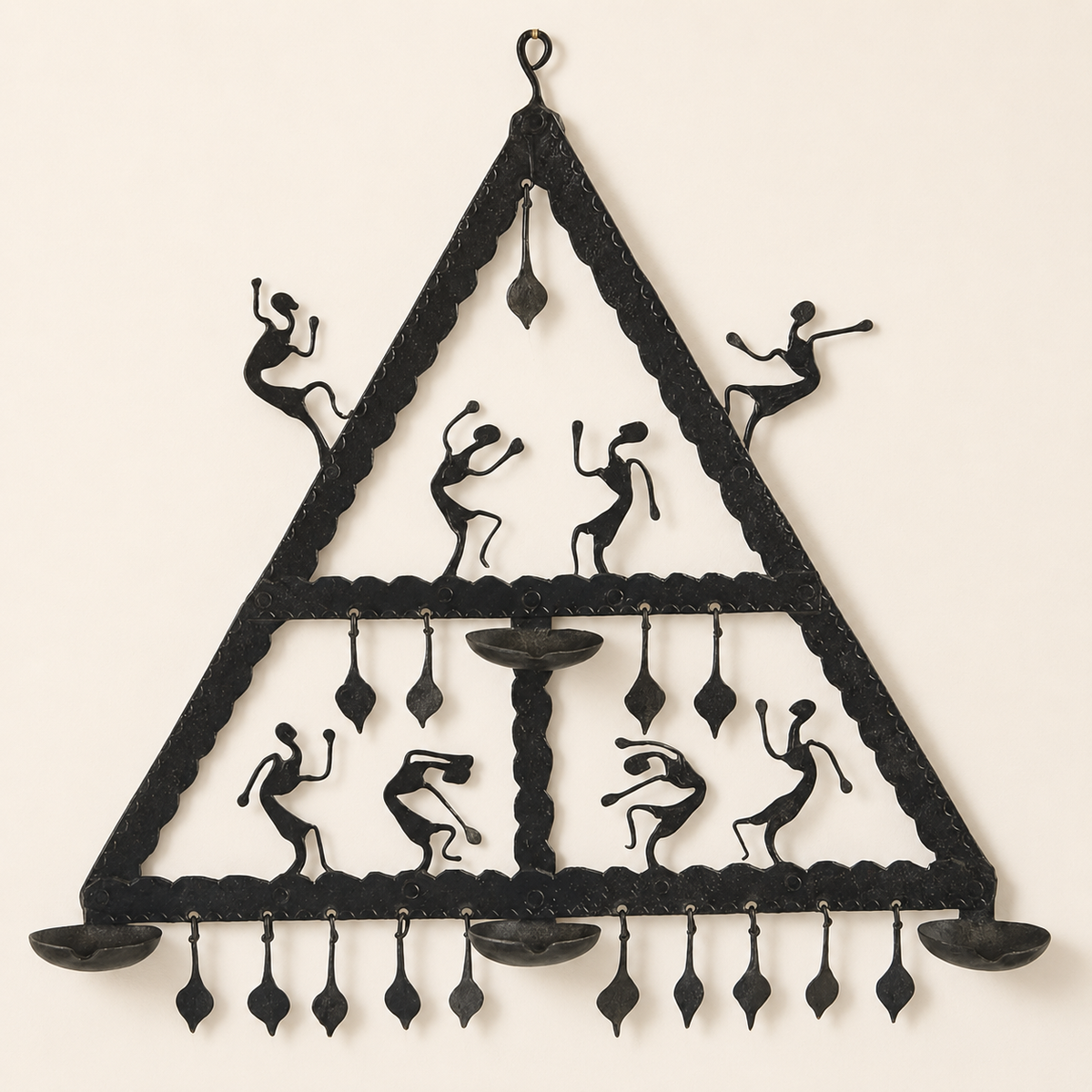 Bastar wrought iron triangular wall candle holder with eight dancers on an ivory wall